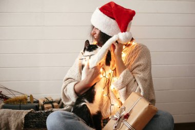 Sevimli kedi şenlikli şık mutlu kız santa şapka ile oynuyor