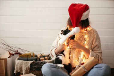Sevimli kedi şenlikli şık mutlu kız santa şapka ile oynuyor