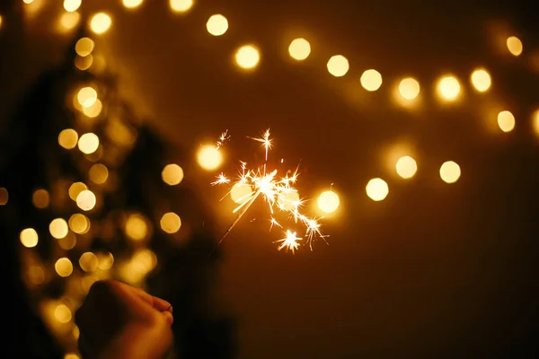 Mano con brillantes destellos en el fondo de la Navidad de oro — Foto de Stock