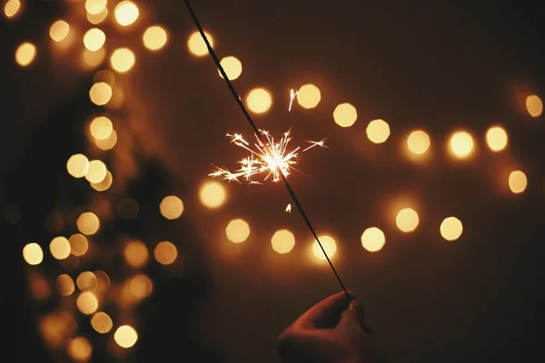 Brillante chispeante en la mano en el fondo del árbol de Navidad de oro — Foto de Stock