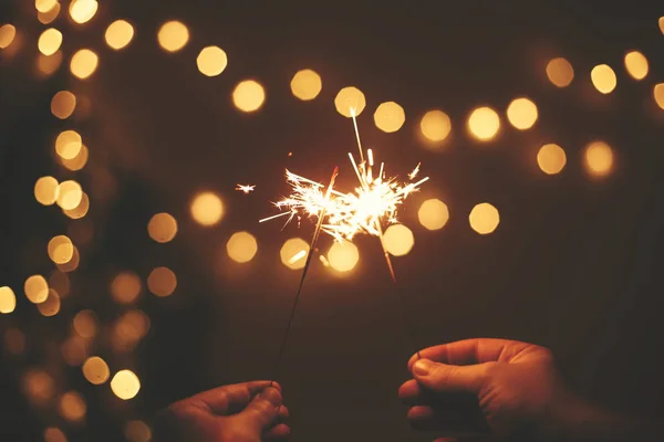 Feliz Año Nuevo. Brillos brillantes en las manos sobre fondo de oro — Foto de Stock