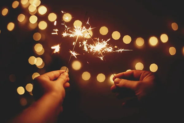 Feliz Año Nuevo. Brillos brillantes en las manos sobre fondo de oro — Foto de Stock