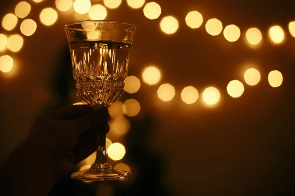 Altın noel l arka plan üzerinde el tutarak şampanya cam — Stok fotoğraf