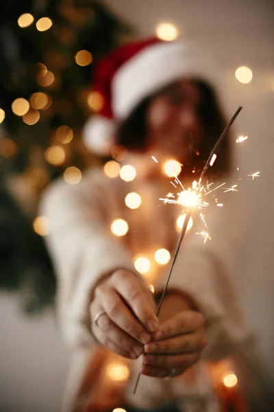 Velký jiskřinka, hořící v rukou stylové dívky v Santa klobouku v BAC — Stock fotografie