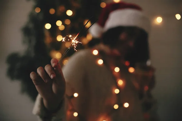 Big sparkler burning in hand of stylish hipster girl in santa ha — Stock Photo, Image