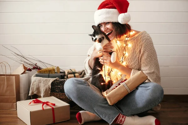 Noel baba şapkalı şık mutlu kız şenlikli sevimli kedi ile oynuyor — Stok fotoğraf