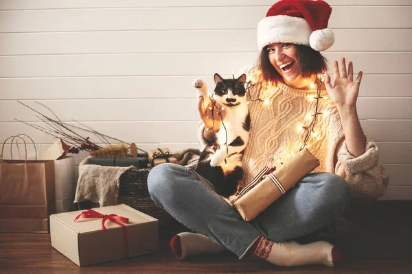 Happy Holidays. Stylish happy girl in santa hat  and cute cat wa — Stock Photo, Image