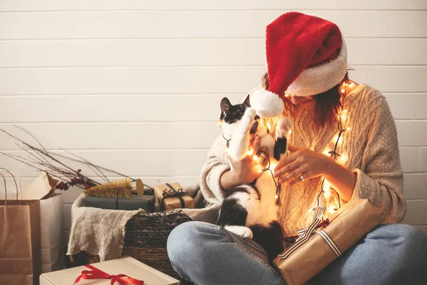 Élégant heureux fille dans santa chapeau jouer avec mignon chat dans festive — Photo