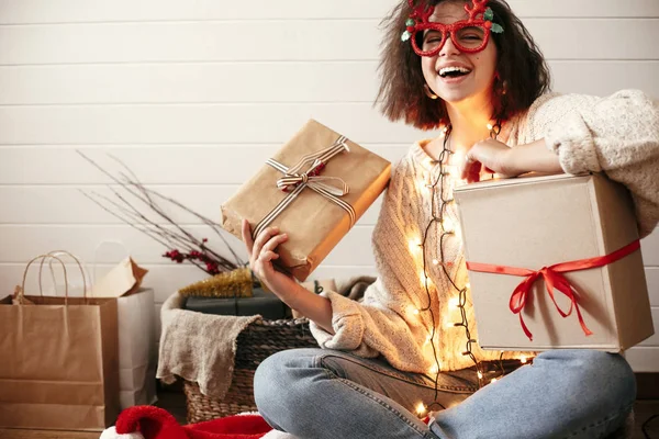 Stylish happy girl in festive glasses with reindeer horns holdin — Stock Photo, Image