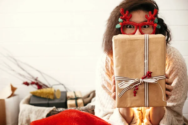 Stylish happy girl in festive glasses with reindeer antlers hold — Stock Photo, Image