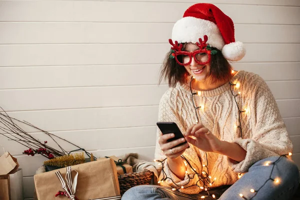 Noel Baba şapkalı şık mutlu kız ve reindee ile şenlikli gözlük — Stok fotoğraf