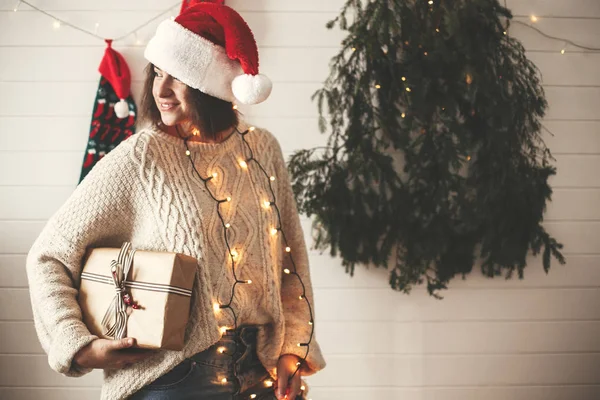 Stylová šťastná dívka v Santa čepici s vánočním dárkem na ba — Stock fotografie