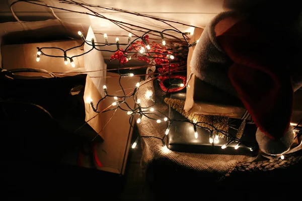 Stylové vánoční dárkové krabice, Santa klobouk, světlíky na vojsku — Stock fotografie