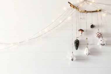 Noel vintage oyuncaklar şenlikli ışıkları ile beyaz duvarda ahşap şube asılı