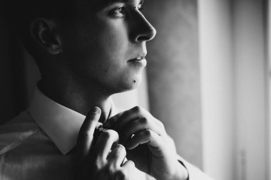 Beyaz gömlek şık damat h pencere yakınında papyon koyarak