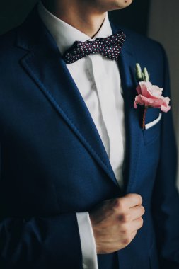 Mavi takım elbiseli şık damat, papyon ve pi ile boutonniere ile