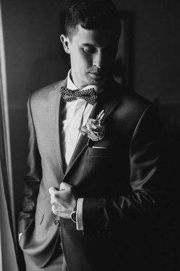 Mavi takım elbiseli şık damat, papyon ve pi ile boutonniere ile