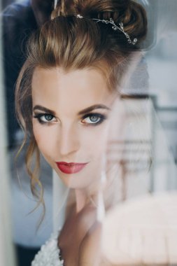 Rüzgara yakın yumuşak ışıkta poz veren inanılmaz makyajlı şık gelin