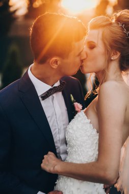 Şık mutlu gelin ve damat biz sıcak günbatımı ışığında öpüşme