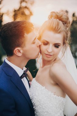 Şık mutlu gelin ve damat biz sıcak günbatımı ışığında öpüşme