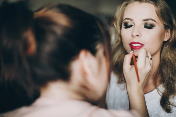 Beautiful happy bride getting her makeup done by professional ma — Stock Photo, Image