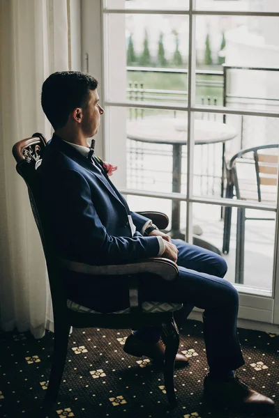 Elegante novio en traje azul, con pajarita y boutonniere con pi — Foto de Stock