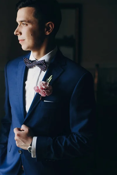 Stylish groom in blue suit, with bow tie and boutonniere with pi — Stock Photo, Image