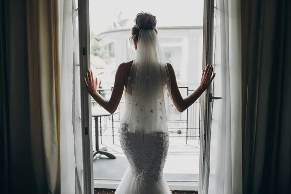Silhueta de noiva elegante janela de abertura varanda em luz suave — Fotografia de Stock