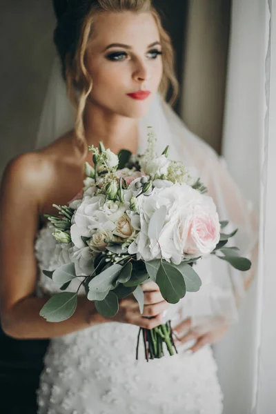 Noiva elegante segurando buquê de casamento moderno e posando em suave — Fotografia de Stock