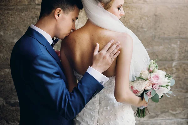 Стильный жених нежно целует прекрасную невесту с букетом в шо — стоковое фото