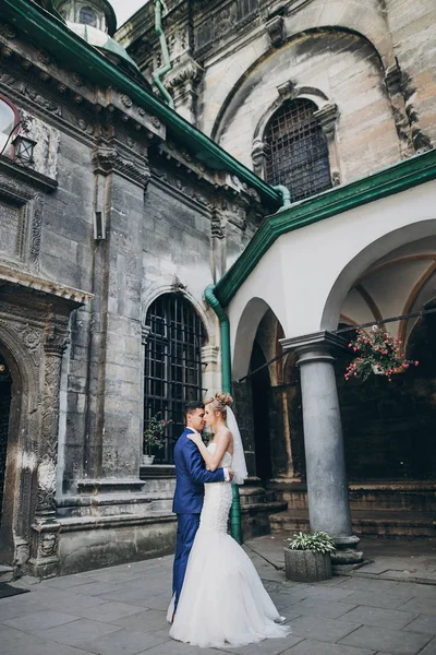 Eleganti sposi che si abbracciano delicatamente nella soleggiata città europea — Foto Stock