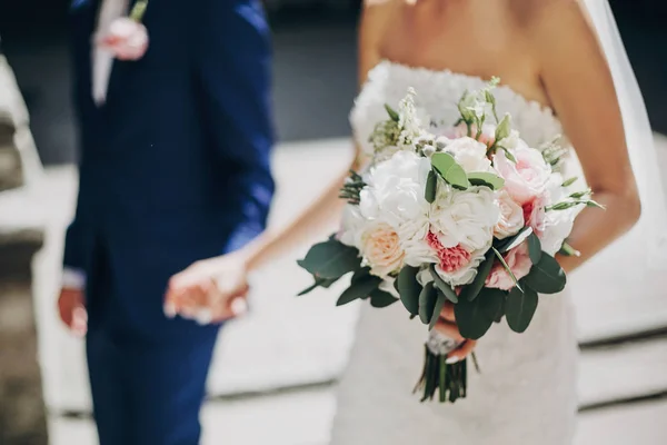 Stylová nevěsta s kyticí a ženichovou chůze v prosluněném evropském c — Stock fotografie