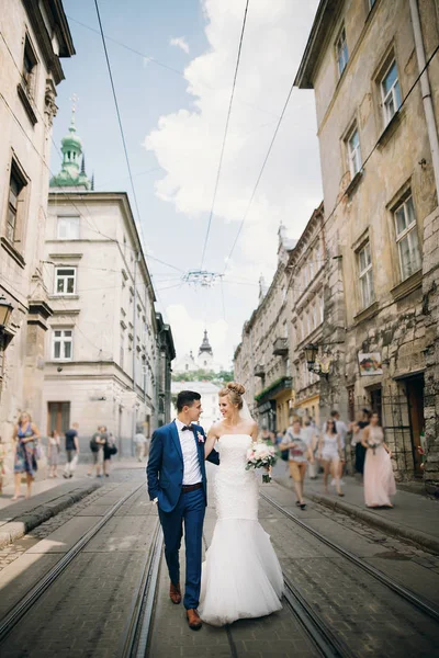 Elegante novia feliz y novio caminando y sonriendo en la ciudad soleada —  Fotos de Stock