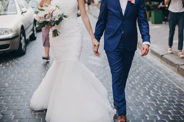 Elegante novia con ramo y novio caminando en soleado c europeo —  Fotos de Stock