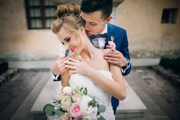 Stylish groom kissing sensually his happy bride in sunny europea — Stock Photo, Image