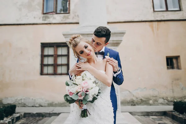Noiva elegante e noivo beijando sensualmente na cidade europeia ensolarada — Fotografia de Stock