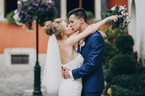 Стильні наречений і наречена цілувалися чуттєво в сонячному європейському місті — стокове фото