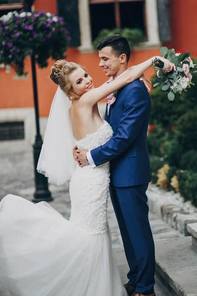 Стильные невеста и жених позируют и улыбаются в солнечном европейском городе — стоковое фото