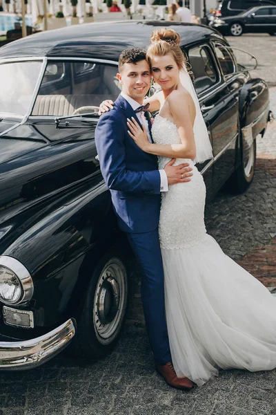 Elegante novia feliz y novio posando en el viejo coche retro. Precioso. —  Fotos de Stock
