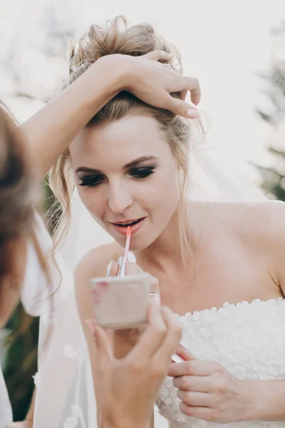 スタイリッシュな花嫁は、彼女のメイクを修正し、ウェディンで口紅を適用 — ストック写真