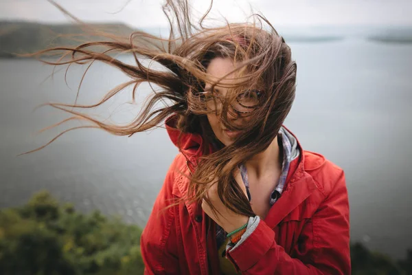 Traveler girl in red raincoat and with windy hair standing on to — Stock Photo, Image