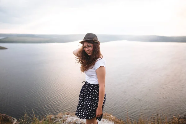 Reisemädchen mit Hut und windigem Haar steht auf einem Felsen — Stockfoto