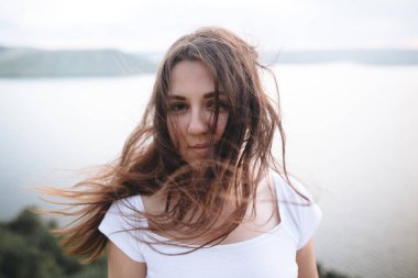 Kayanın üzerinde duran rüzgarlı saçlı hipster kız portresi