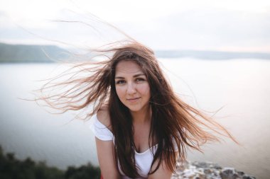 Kayanın üzerinde duran rüzgarlı saçlı hipster kız portresi