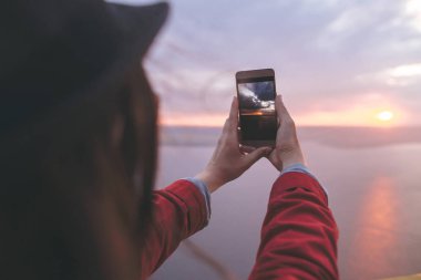 Gezgin kız telefon tutan ve güzel evenin fotoğraf çekmek
