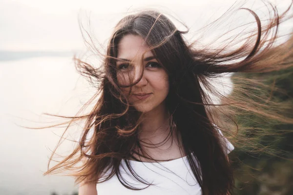 Portrait of hipster girl with windy hair standing on top of rock — Stock Photo, Image