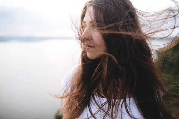 Portrait of hipster girl with windy hair standing on top of rock — Stock Photo, Image