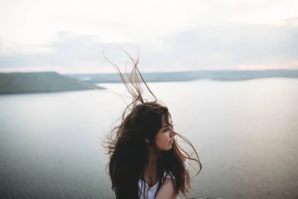 Porträt eines Hipster-Mädchens mit windigen Haaren, das auf einem Felsen steht — Stockfoto