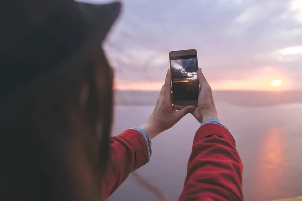 Chica viajero sosteniendo el teléfono y tomar una foto de la hermosa evenin — Foto de Stock