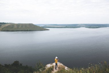 Hipster genç kaya dağın tepesinde duran ve bakıyor